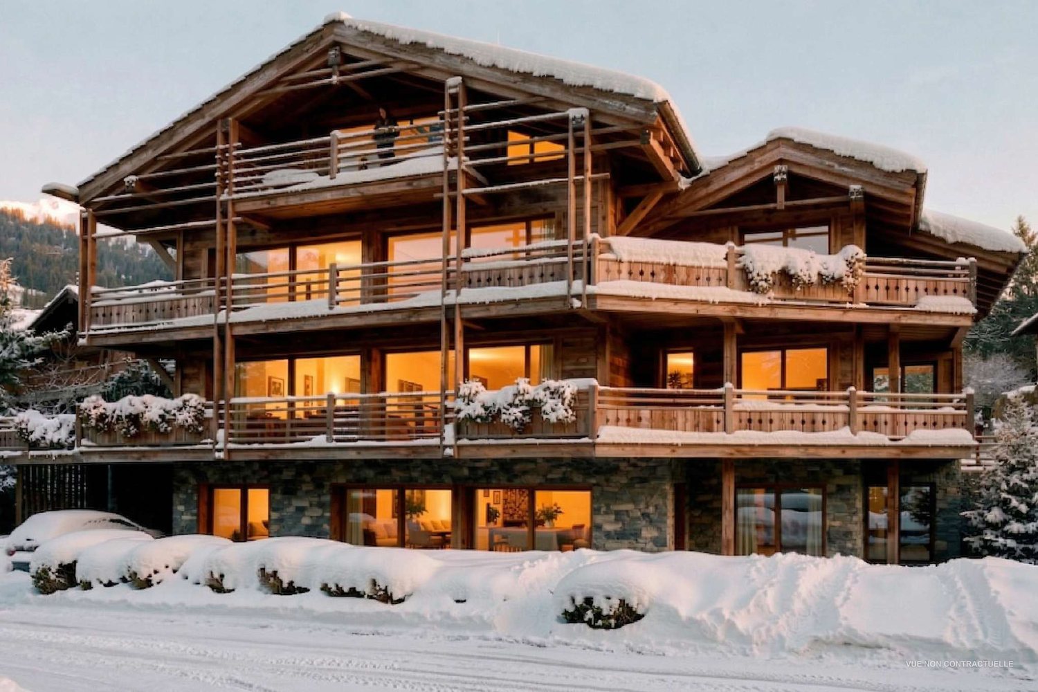 Vue de synthèse de la résidence en hiver, sous la neige, fenêtres éclairées à la tombée du jour.